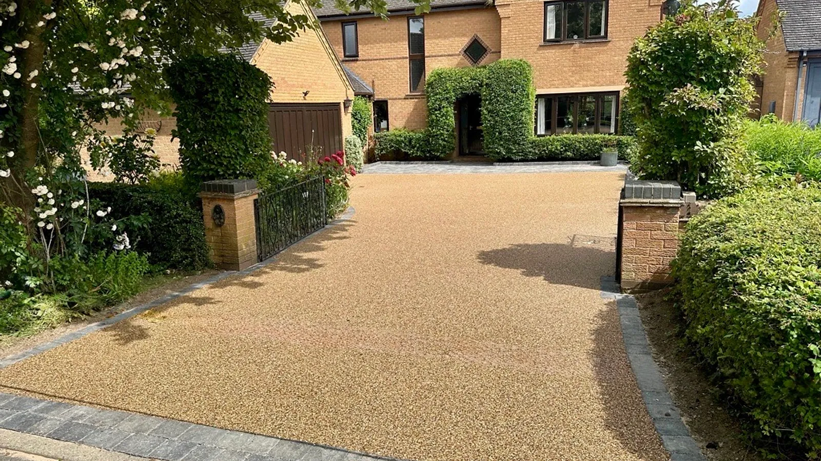 A resin bound driveway with block-paved border leading to a large detached home, by Holmes Landscapes